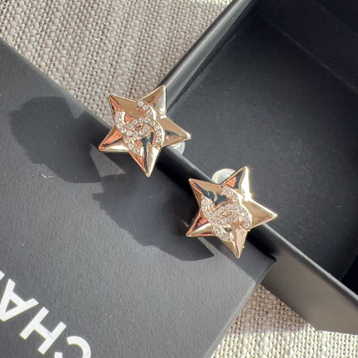 Star-shaped earrings on a black box with 'Chanel' branding.