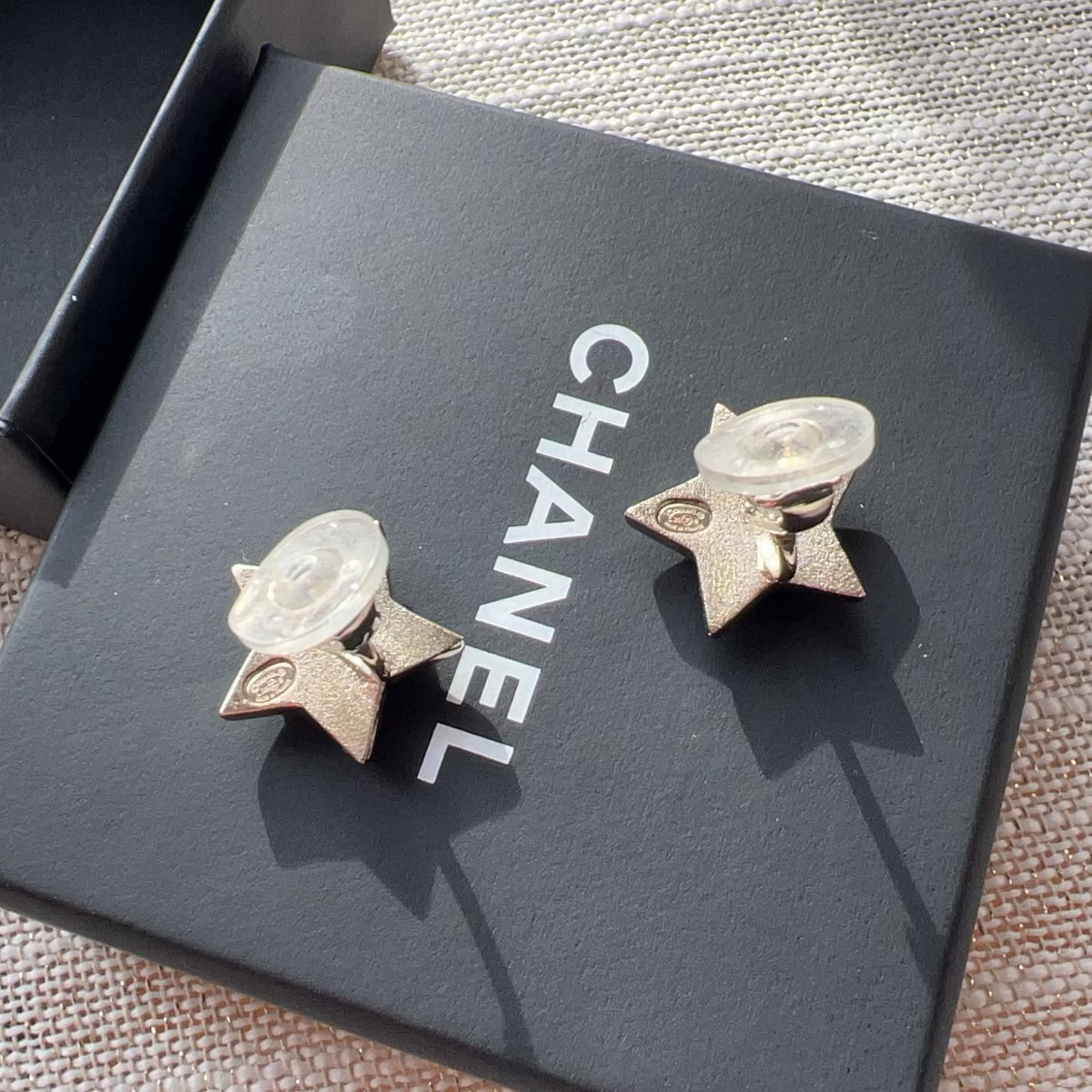 Chanel earrings on a black box with 'Chanel' branding.