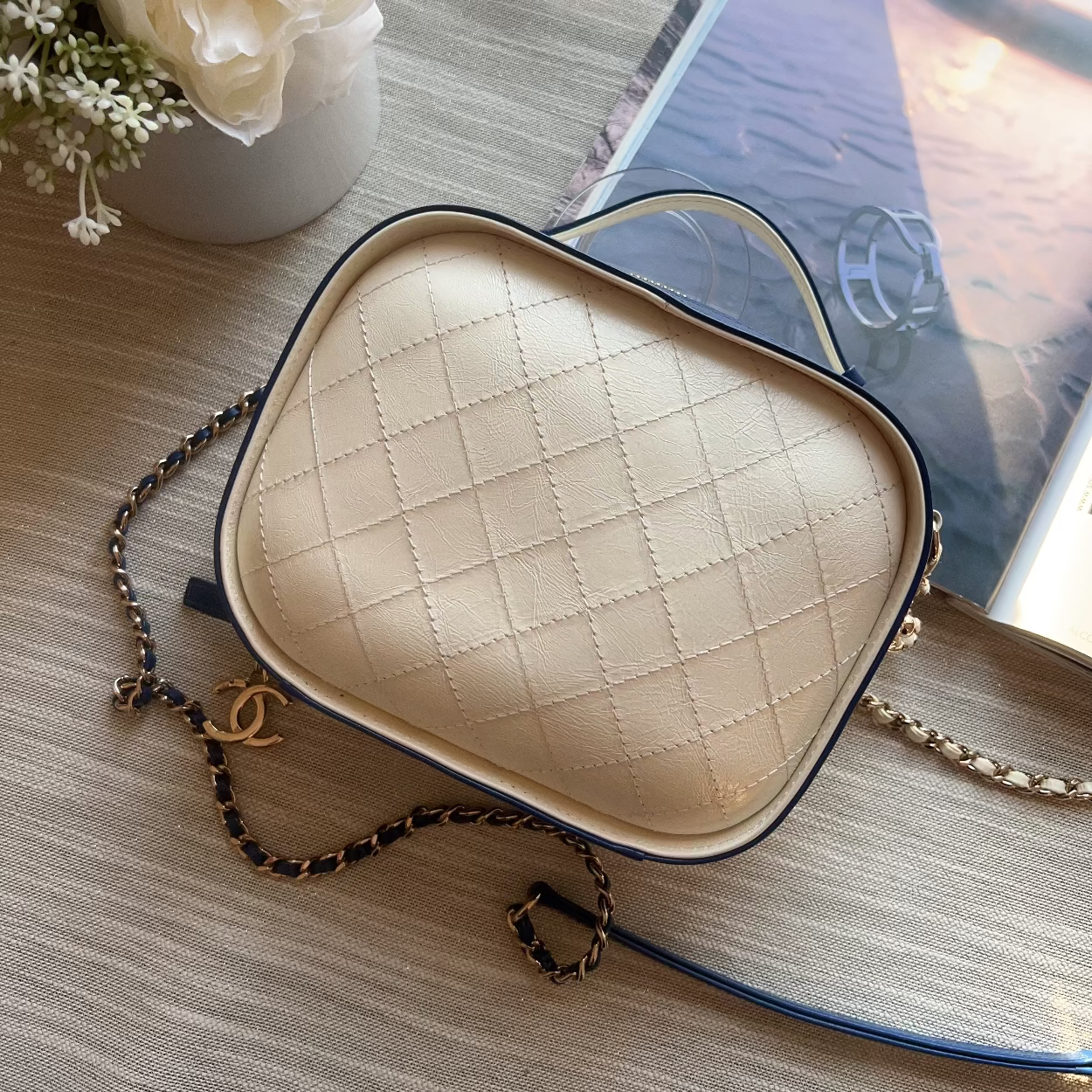 Heart-shaped beige bra with a chain on a wooden surface with flowers and a book in the background
