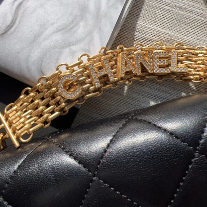 Gold Chanel bracelet on a black quilted handbag with a marble background