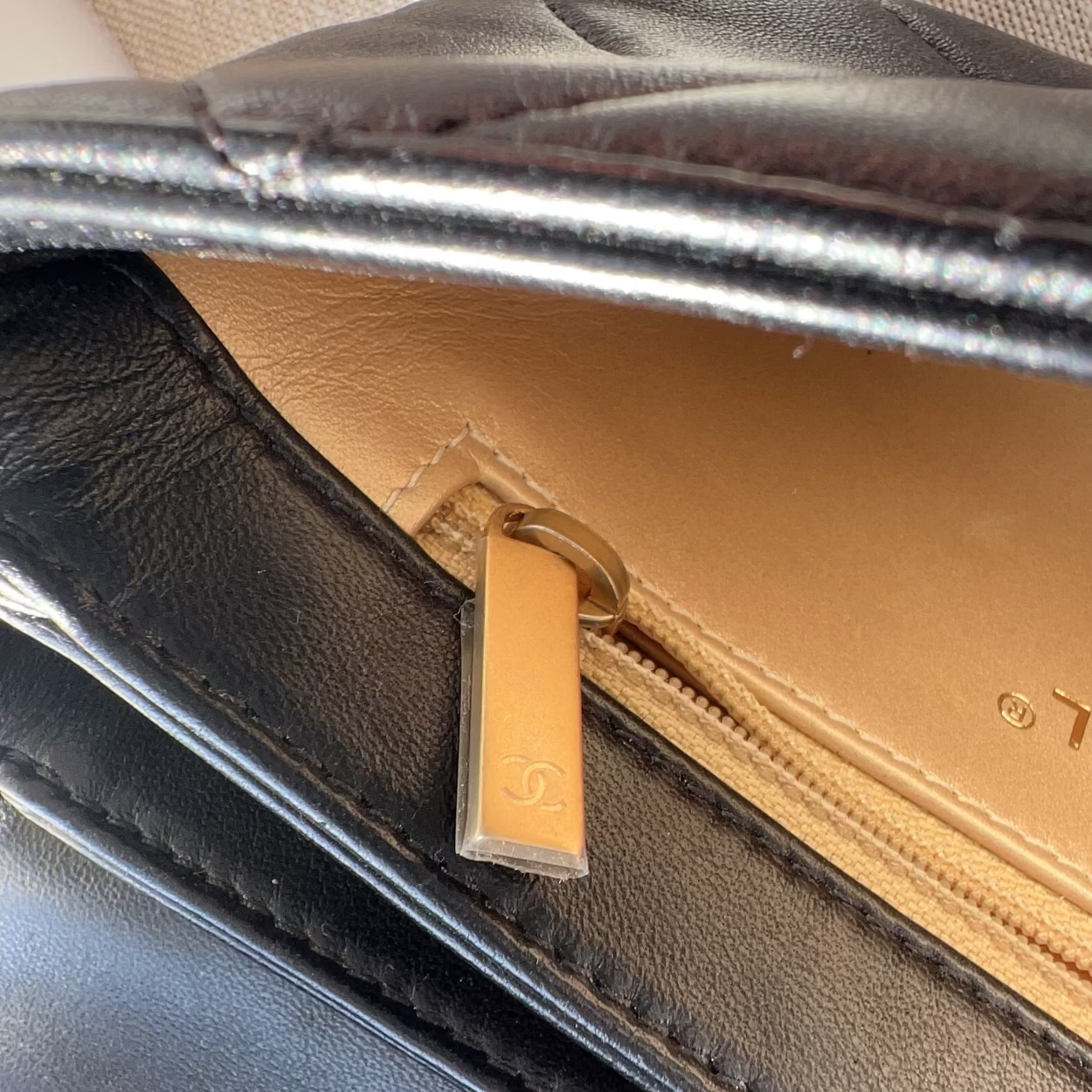 Close-up of a black leather bag with a gold zipper pull.