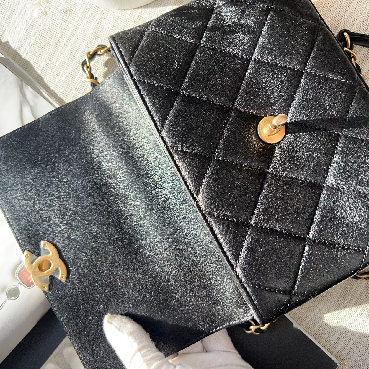 Black quilted handbag with gold chain strap on a light wooden surface