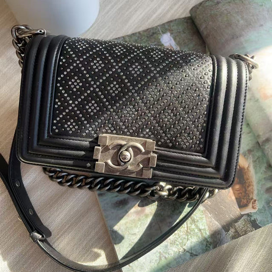 Black studded handbag with Chanel logo on a textured surface