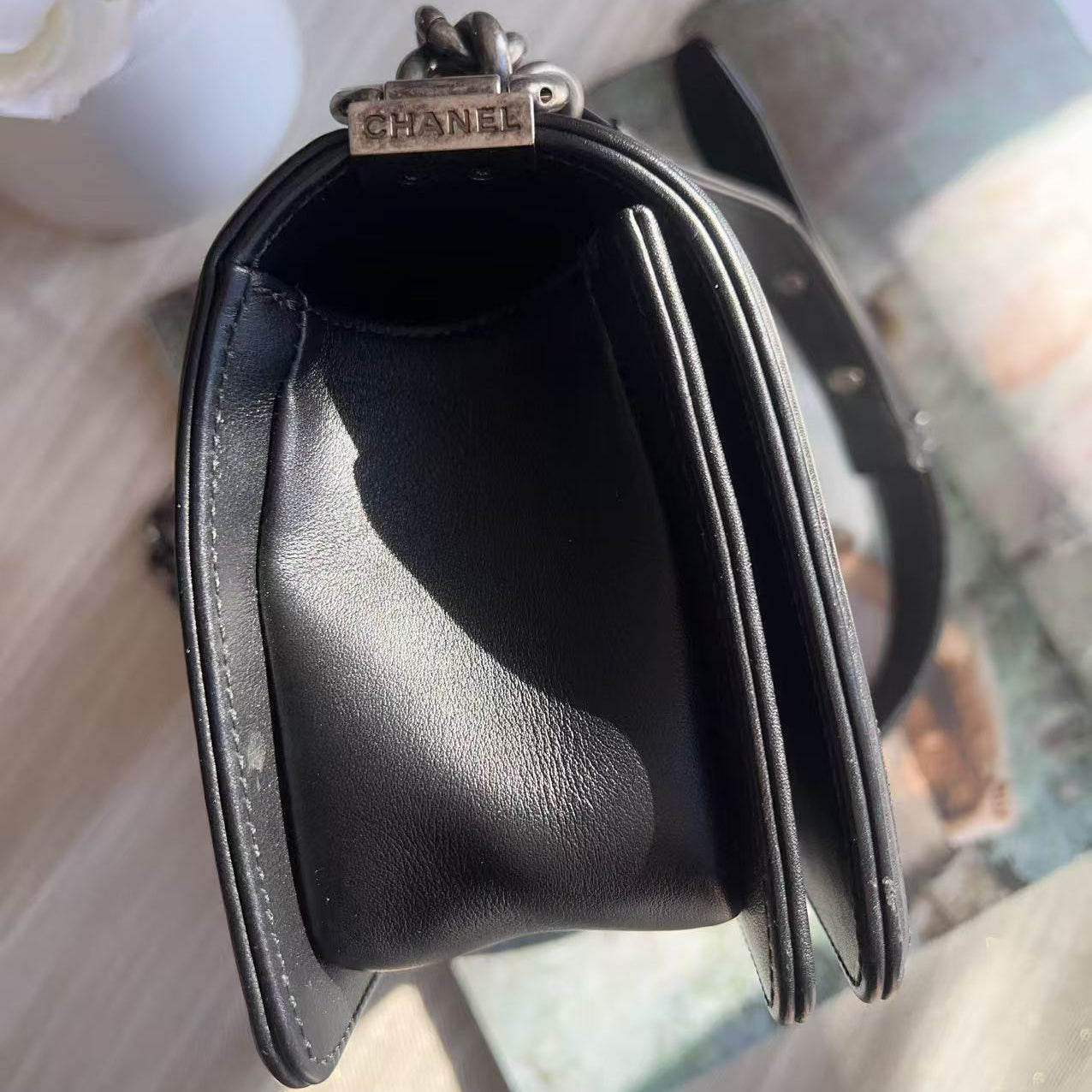 Black Chanel handbag on a light wooden surface with a blurred background