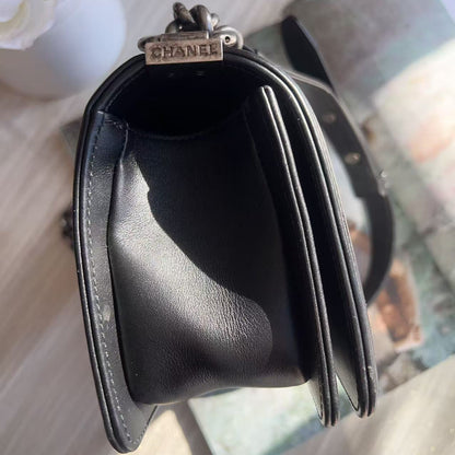 Black Chanel handbag on a light wooden surface with a blurred background