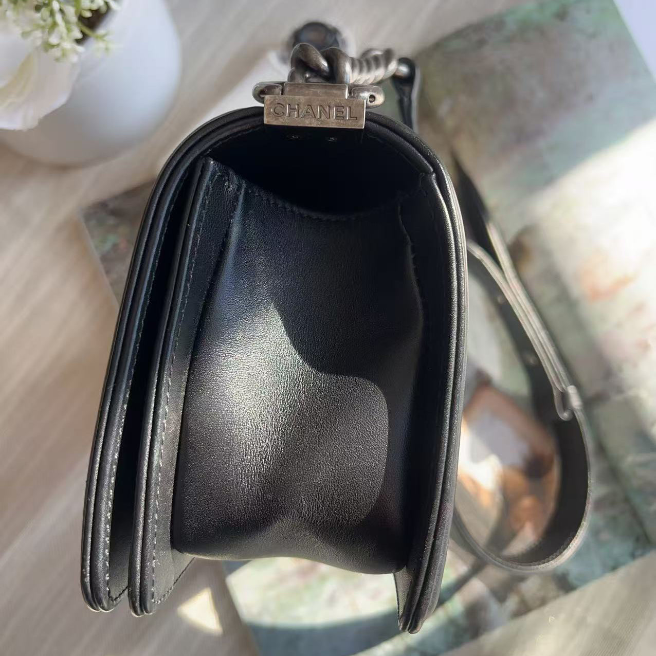 Black Chanel handbag on a textured surface with a blurred background