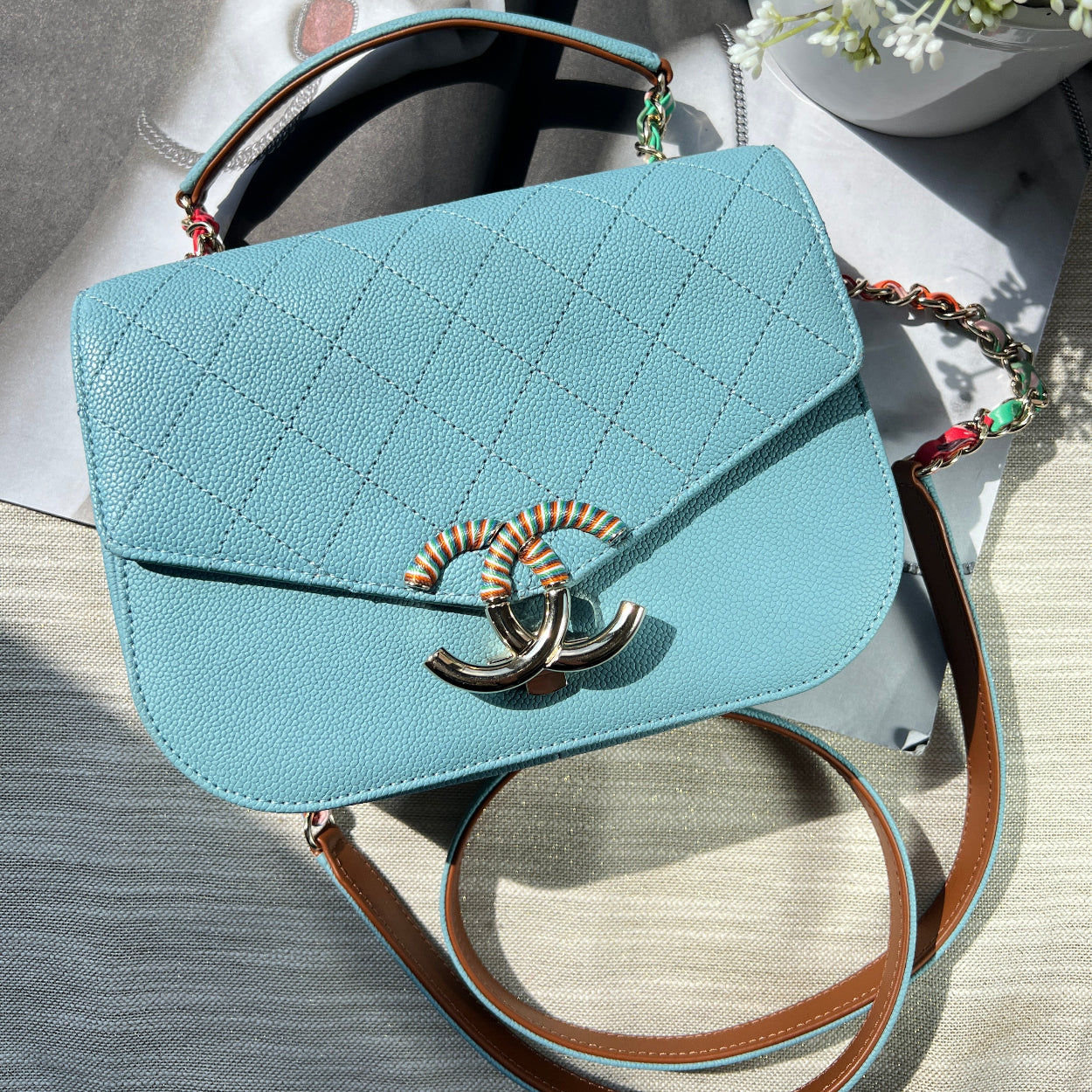 Light blue handbag with a brand logo on a textured surface