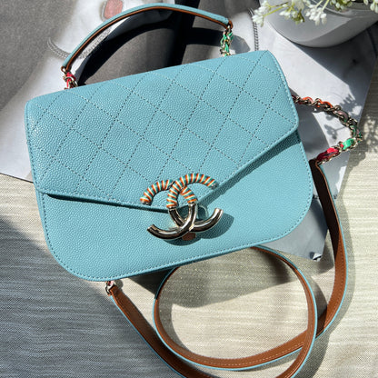 Light blue handbag with a brand logo on a textured surface