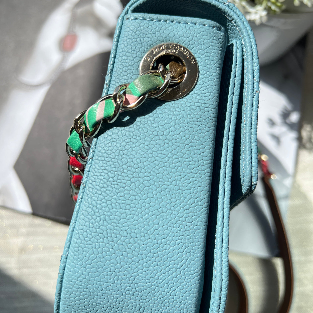 Light blue wallet with a chain strap on a blurred background