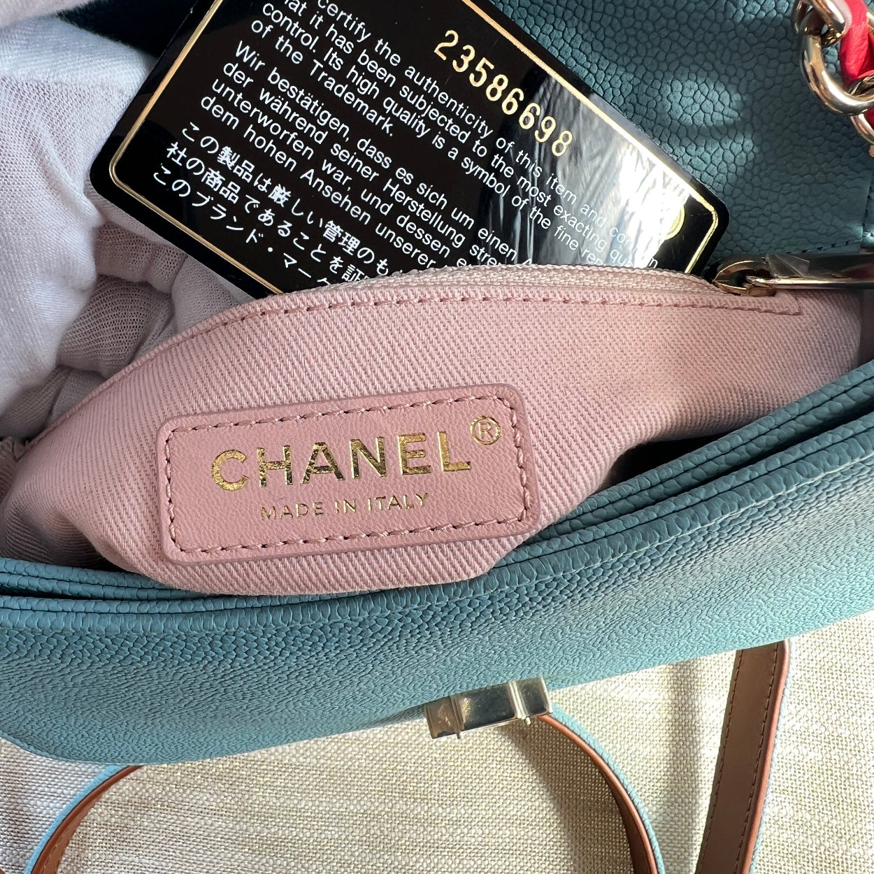 Chanel handbag with a pink tag and visible serial number on a textured surface.