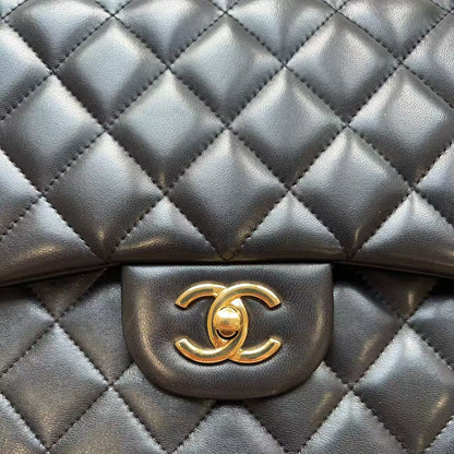A close-up of a black quilted leather handbag with a gold-tone interlocking CC logo clasp, showing the signature diamond pattern and textured leather.