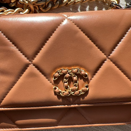 Brown quilted handbag with gold chain detail on a textured surface
