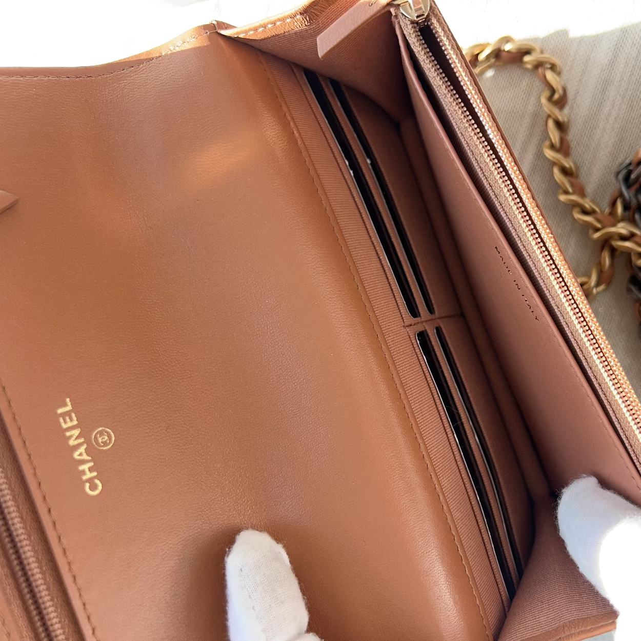 Brown Chanel handbag with a chain strap held by white gloves