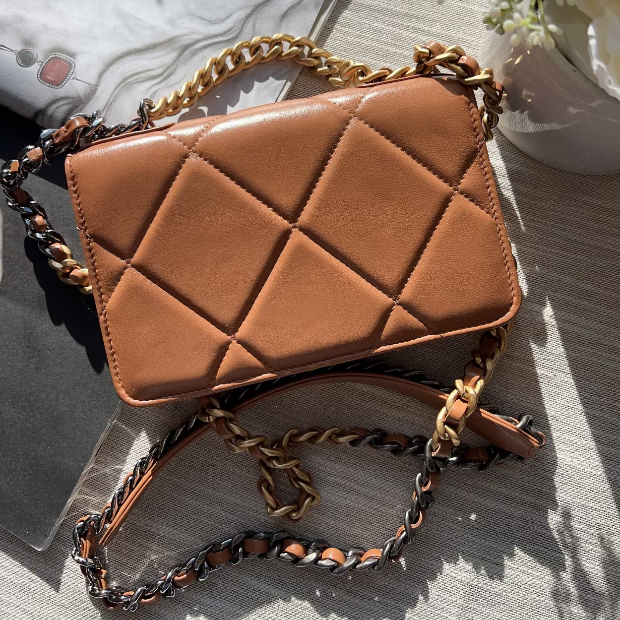 Brown quilted handbag with chain strap on a textured surface