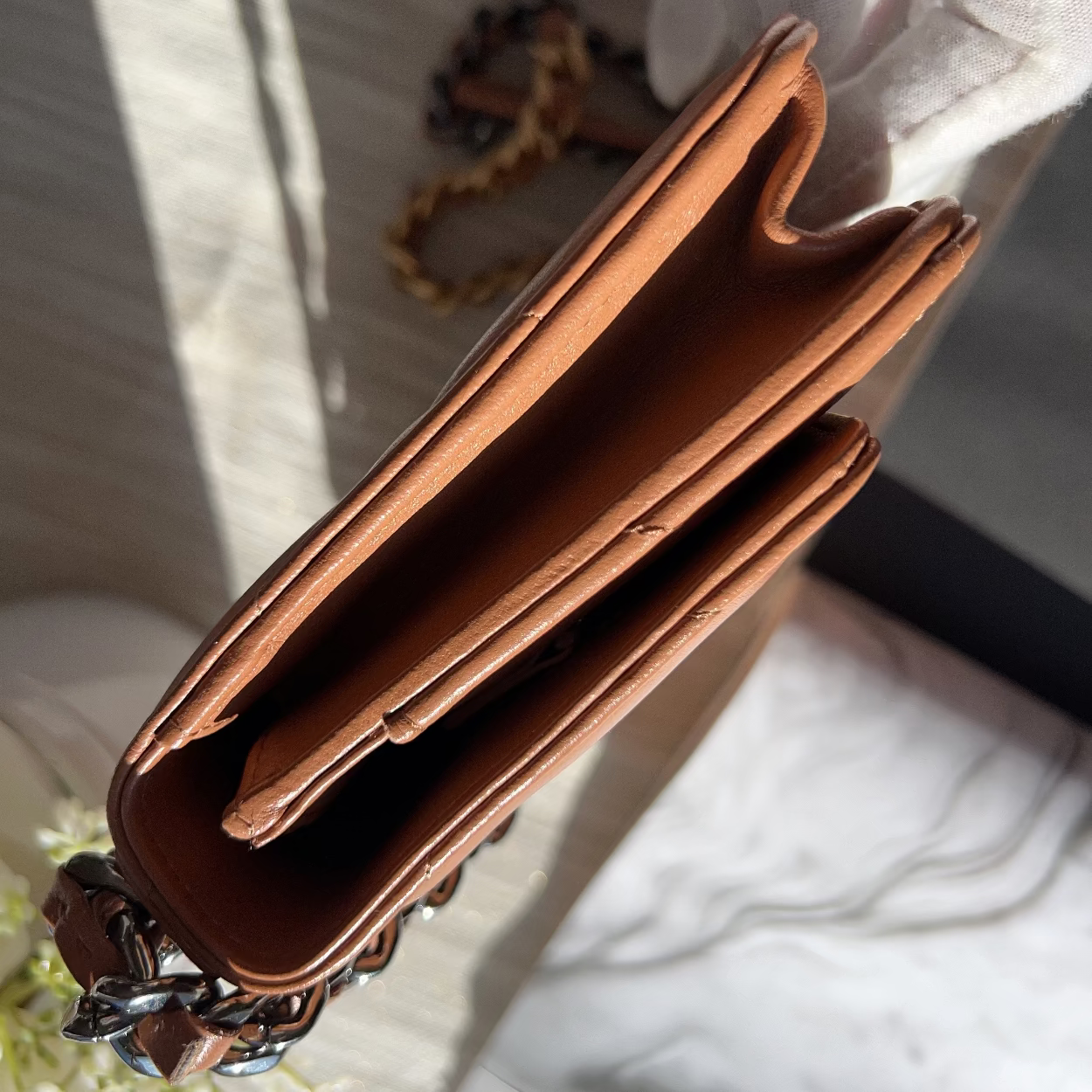 Brown leather wallet with chain detail on a white surface