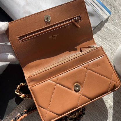 Brown leather handbag with chain strap on a textured surface