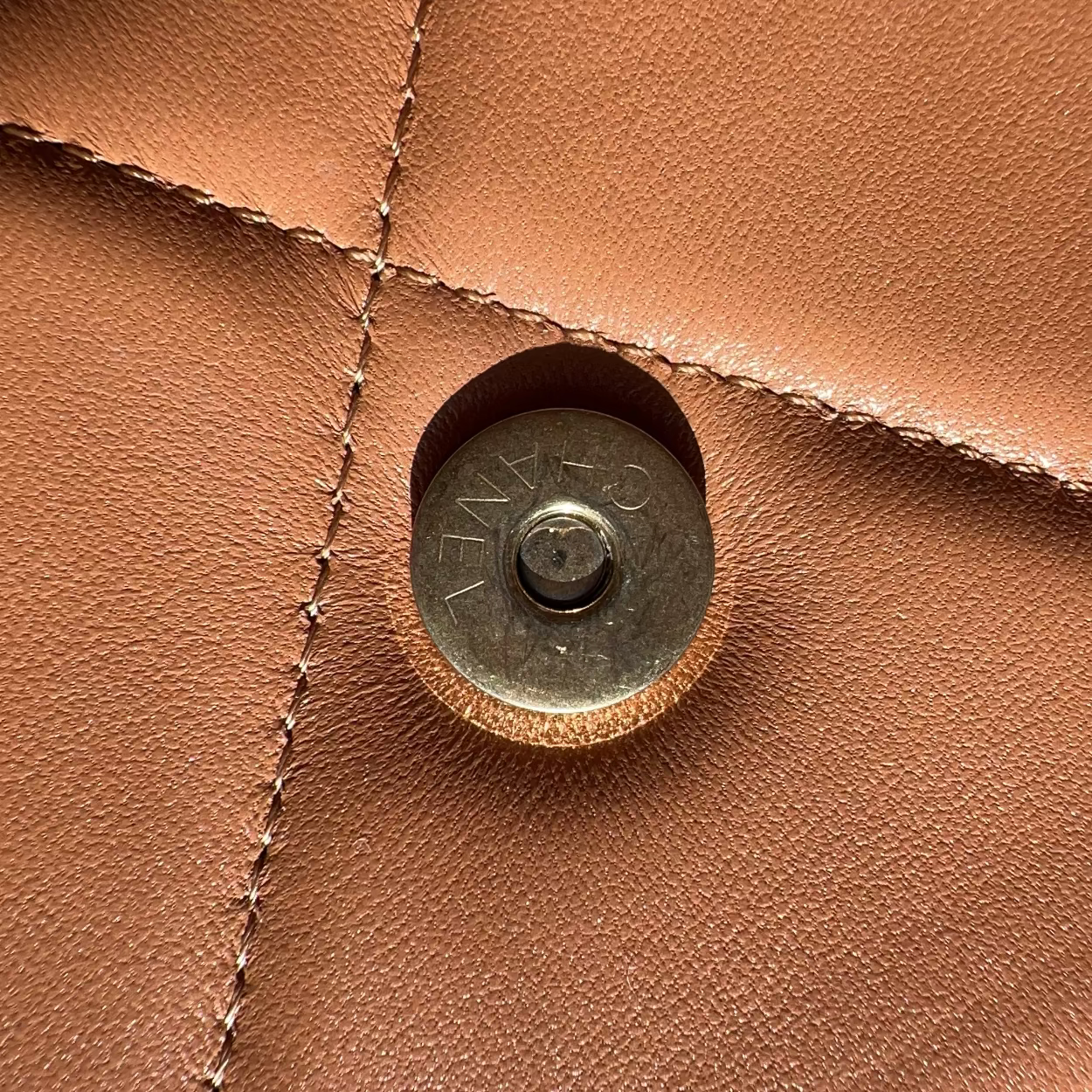 Close-up of a brown leather surface with a metal button.