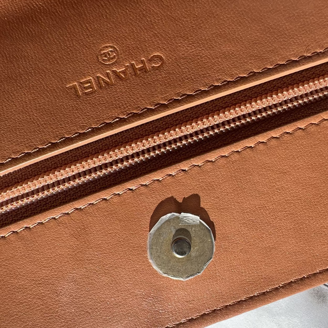 Close-up of a brown leather bag with a visible brand logo on a light gray background