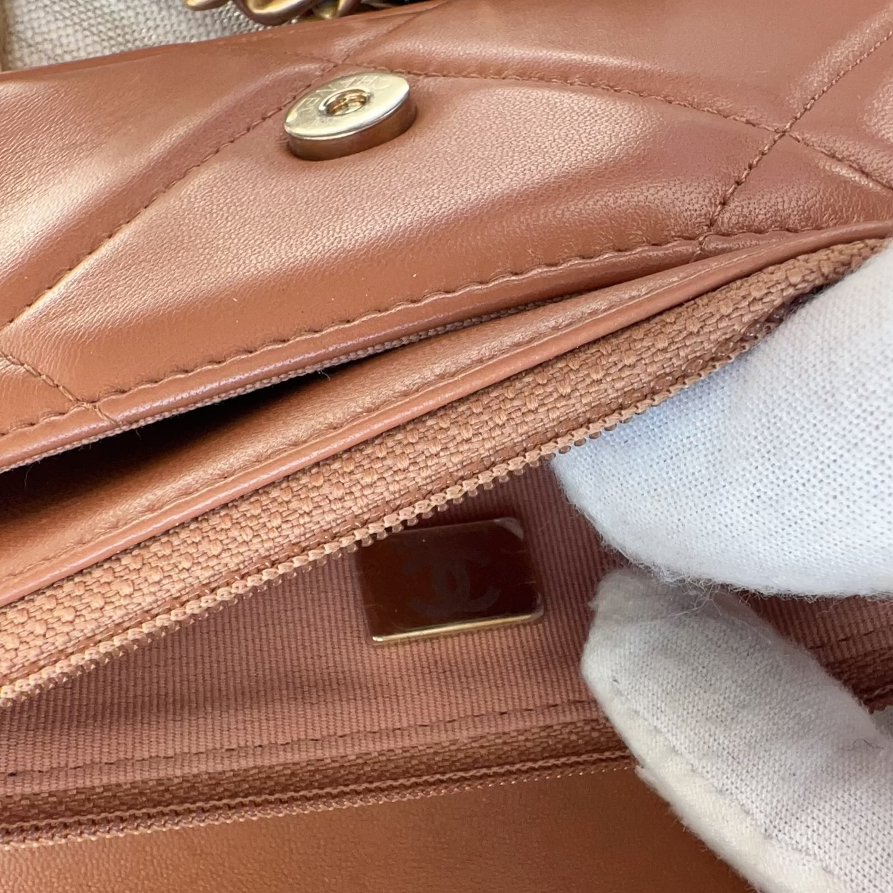 Close-up of a brown quilted handbag with gold hardware.