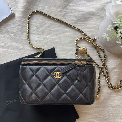 A black quilted leather shoulder bag with a gold-tone chain strap and a gold interlocking CC logo, displayed on a black dust bag over a beige fabric background.