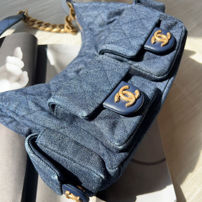 Blue quilted handbag with gold hardware on a light gray surface