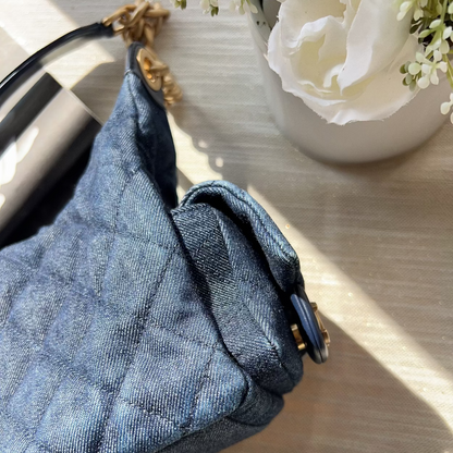 Blue textured handbag on a light wooden surface with a white flower in the background