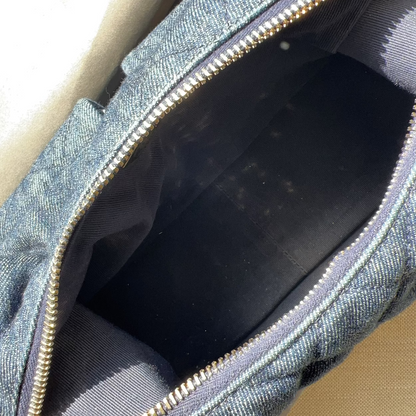 Close-up of a blue denim bag with gold zipper on a beige surface