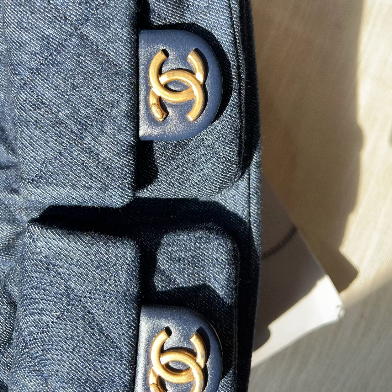 Close-up of a Chanel bag with gold CC logo on a textured surface