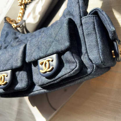 Close-up of a Chanel handbag strap with gold hardware on a textured surface.