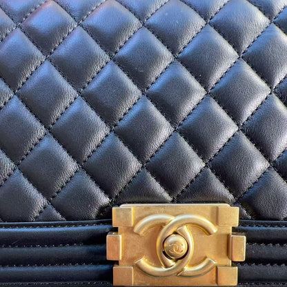 Close-up of a quilted navy blue leather handbag with a prominent gold-tone interlocking CC clasp, showing the texture of the leather and the hardware detail.