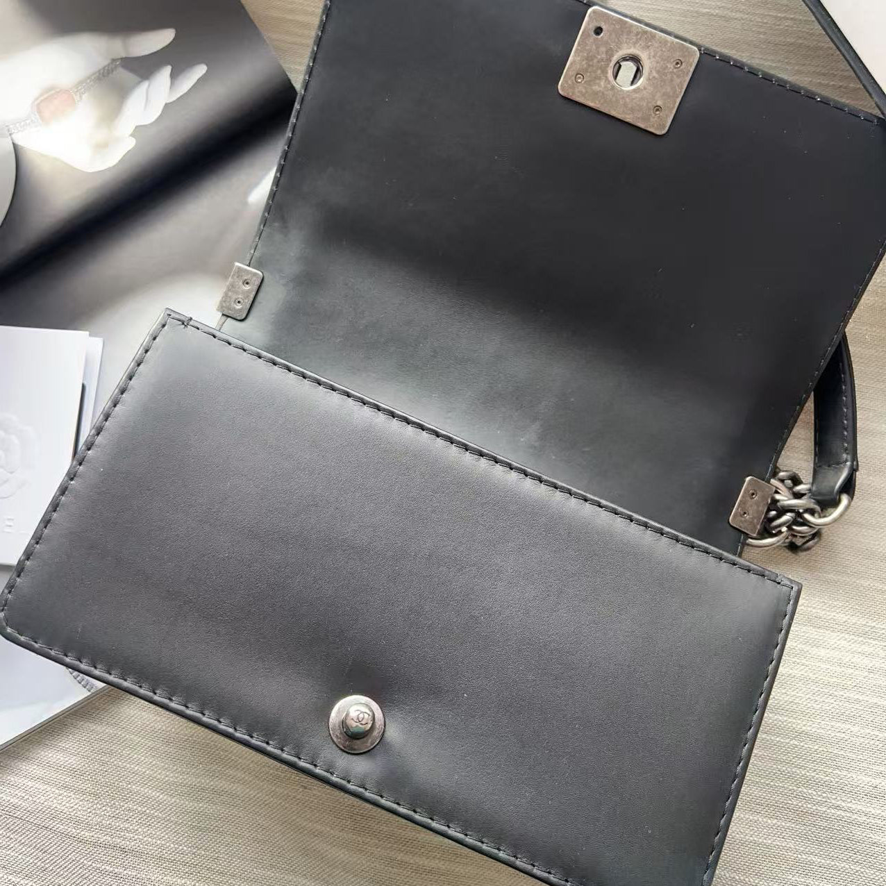 Two black leather bags with metal clasps on a light wooden surface.