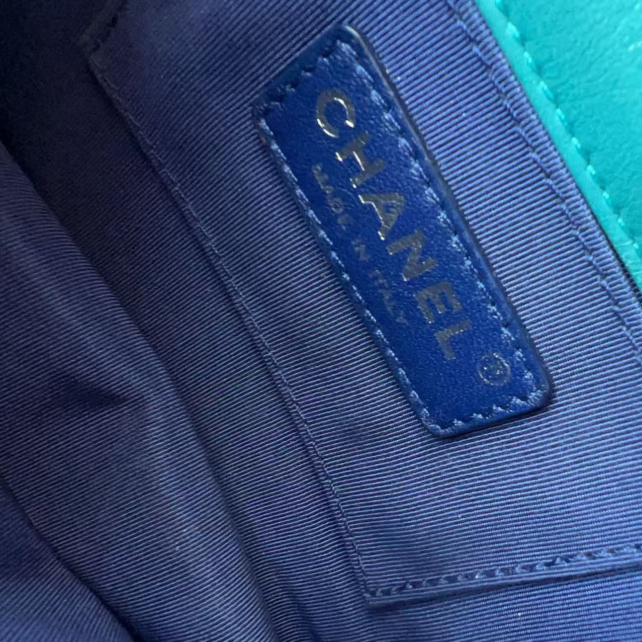 Close-up of a Chanel interior label stitched onto a blue fabric pocket, next to a bright turquoise leather surface.