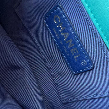 Close-up of a Chanel interior label stitched onto a blue fabric pocket, next to a bright turquoise leather surface.
