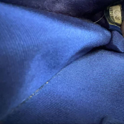 Close-up of a blue fabric garment with a finger pointing to a small sewn-in size tag.