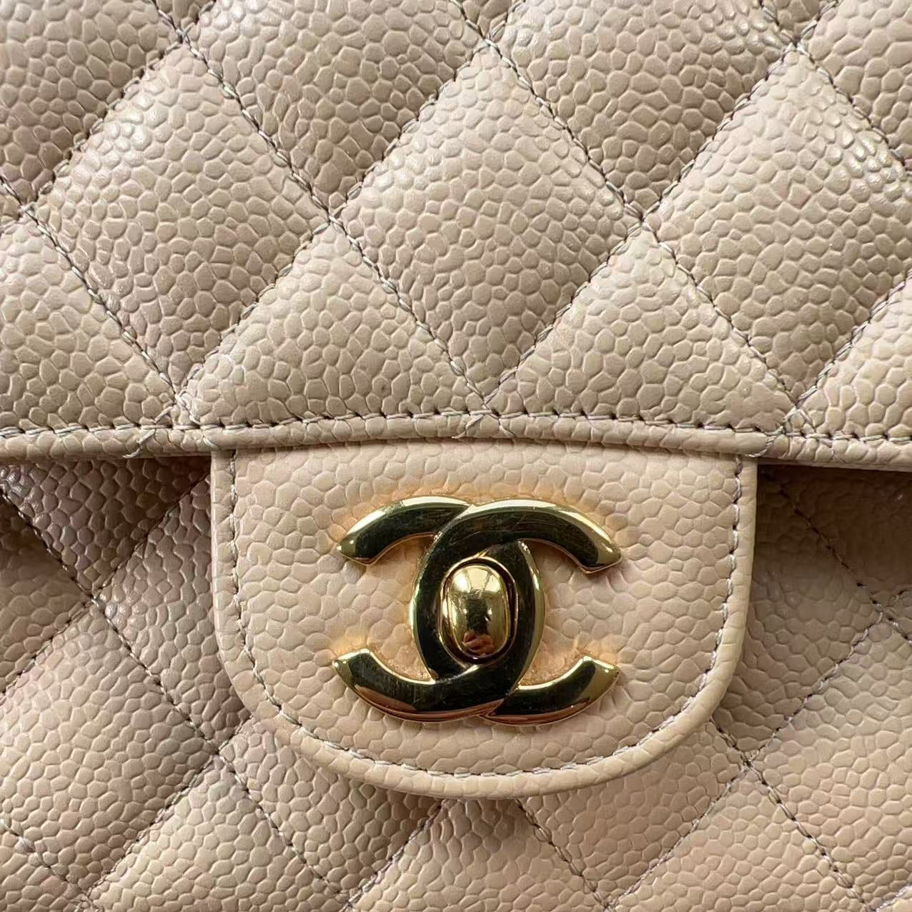 Close-up of a quilted beige handbag with a gold Chanel logo.