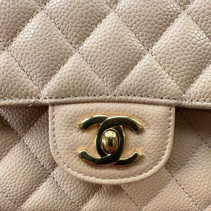 Close-up of a quilted beige handbag with a gold Chanel logo.