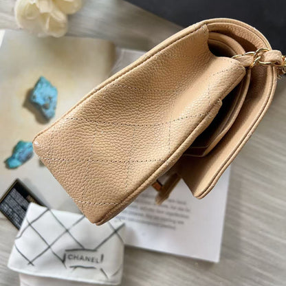 Beige handbag on a surface with a Chanel towel and decorative items.