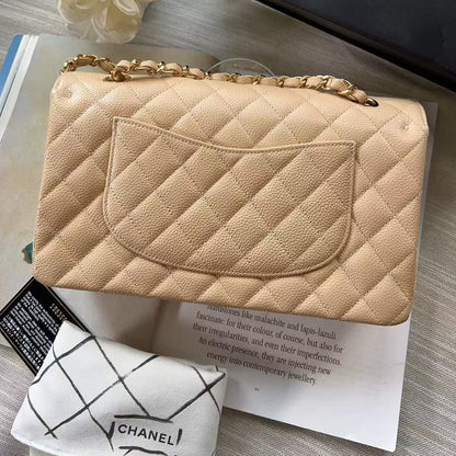 Beige quilted handbag with gold chain on a magazine with Chanel branding.