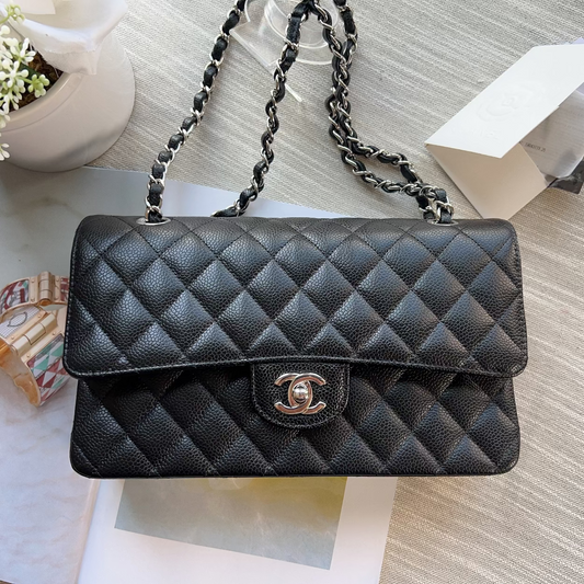 Black quilted handbag with chain strap on a textured surface