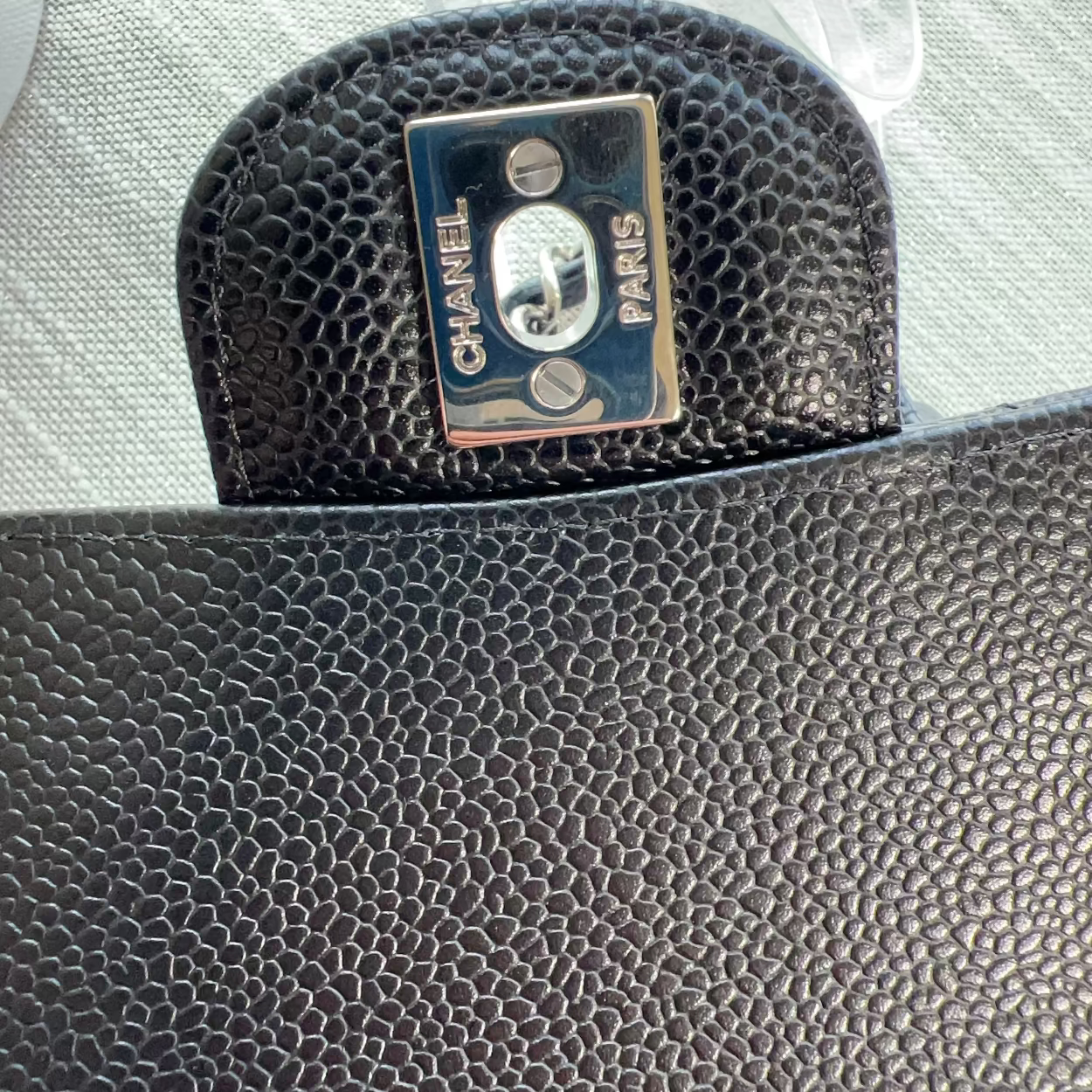Black textured Chanel pouch with logo on a light gray background