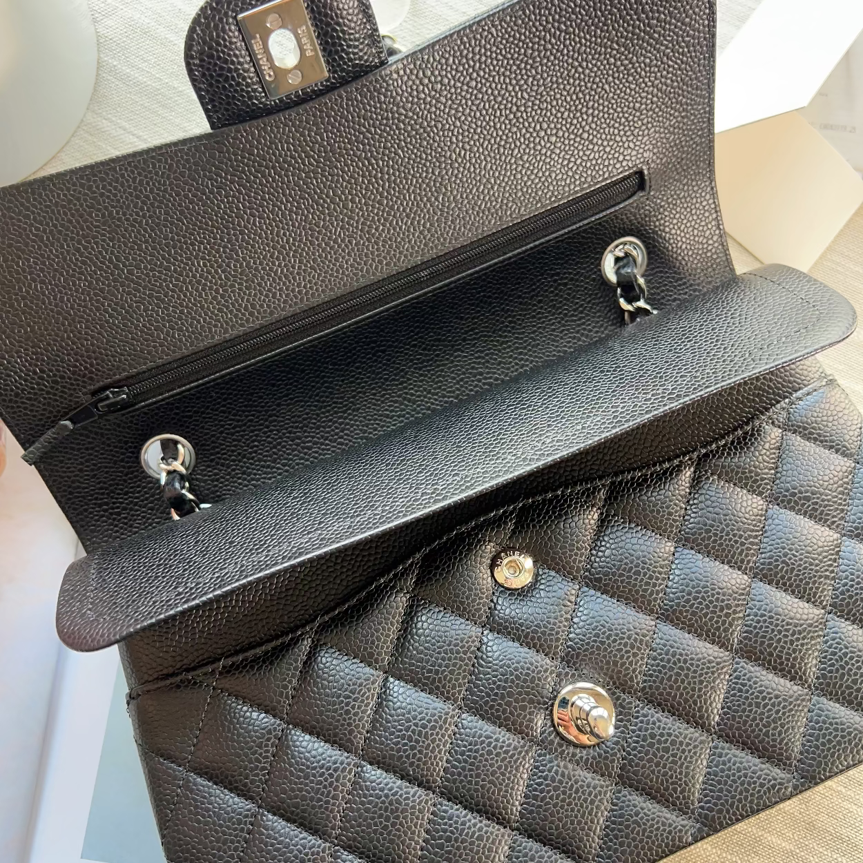 Black quilted handbag with gold hardware on a light wooden surface