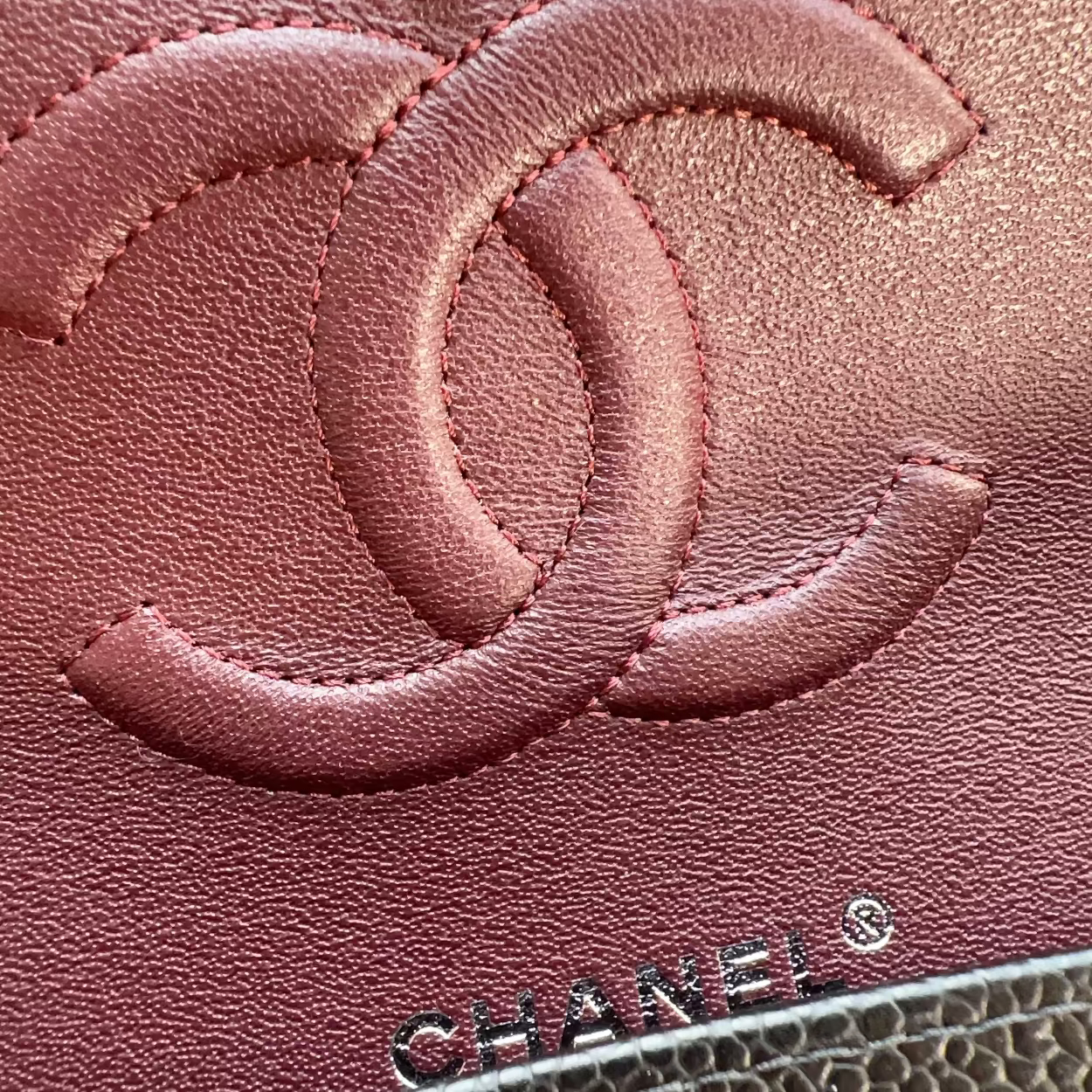 Close-up of a Chanel handbag with the brand logo on a pink leather surface.