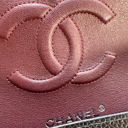 Close-up of a Chanel handbag with the brand logo on a pink leather surface.