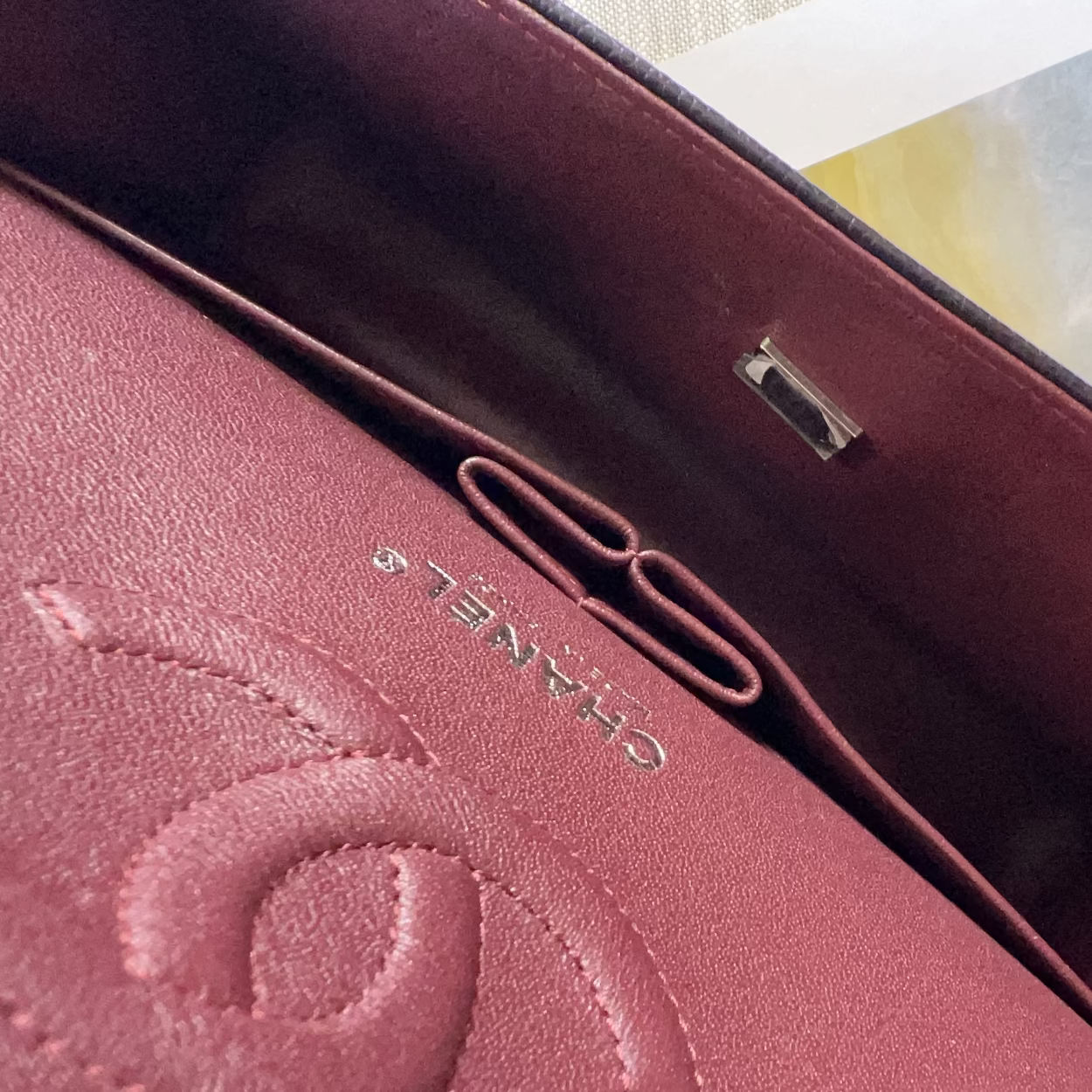 Close-up of a burgundy handbag with 'Chanel' branding.