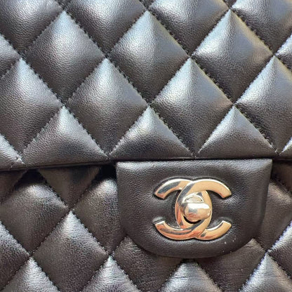 Close-up of a black quilted leather handbag with a prominent gold-tone interlocking CC turn-lock clasp, showing the texture and stitching details.