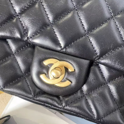 Black quilted handbag with gold Chanel logo on a textured surface