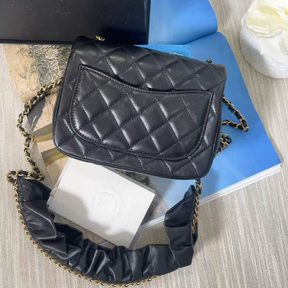 Black quilted handbag with gold chain on a textured surface