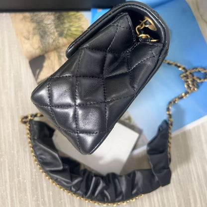 Black quilted handbag with gold chain on a textured surface