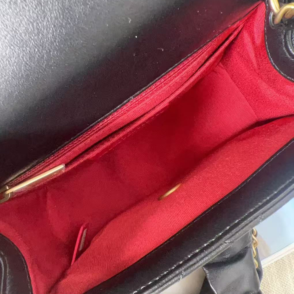 Close-up of a black handbag with red interior lining.