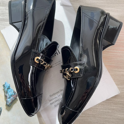 Black patent leather shoes with gold accents on a textured surface